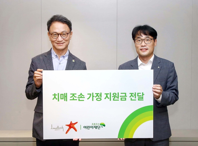 21일, 서울시 송파구 한국룬드벡 본사에서 오필수 한국룬드벡 대표(왼쪽)가 박수봉 초록우산 어린이재단 서울지역본부장(오른쪽)에게 치매 조손가정을 위한 지원금을 전달하고 있다.